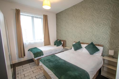 a hotel room with two beds and a window at Ideal for groups - 2 Bedroom Apartment - Free Parking, Transit links, Close to Stadiums in Manchester