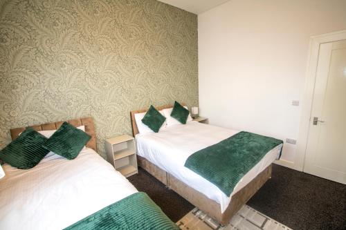 two beds in a room with green and white at Ideal for groups - 2 Bedroom Apartment - Free Parking, Transit links, Close to Stadiums in Manchester