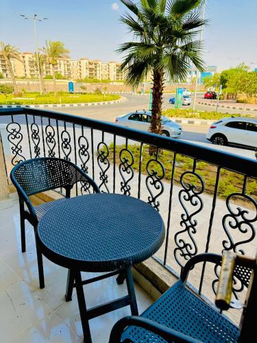 a table and chairs on a balcony with a palm tree at 2BD prime apartment in rehab city in New cairo