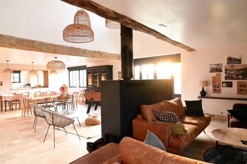 a living room with leather furniture and a dining room at La Grange et le Nid in Saint-Pierre-des-Nids