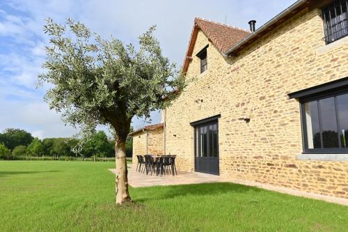 a tree in front of a building with a yard at La Grange et le Nid in Saint-Pierre-des-Nids
