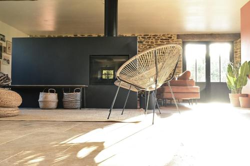 a rattan chair in a living room with a couch at La Grange et le Nid in Saint-Pierre-des-Nids
