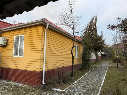 a yellow house with a brick sidewalk in front of it at Gabala Homes Musa in Gabala