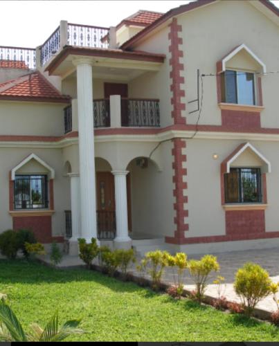 a large house with columns and a yard at Paradise Estate in Gambia in Old Yundum