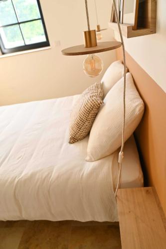 a bedroom with a white bed with a lamp at La Grange et le Nid in Saint-Pierre-des-Nids
