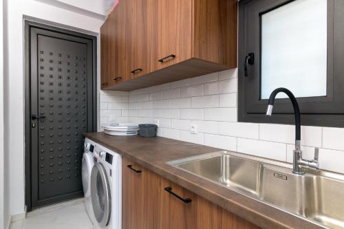 a kitchen with a sink and a washing machine at Villa Galini in Haraki