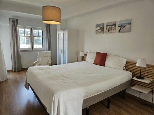 a bedroom with a large white bed and a chair at Bolina 2 Historic Center Cascais in Cascais