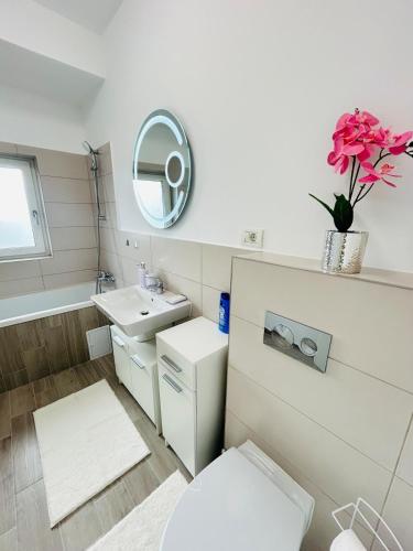 Un baño con inodoro, lavabo y espejo. en Chic city home, en Timisoara