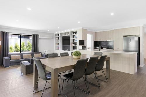 a kitchen and living room with a wooden table and chairs at 5 Bedroom Home meters from the beach in Geographe