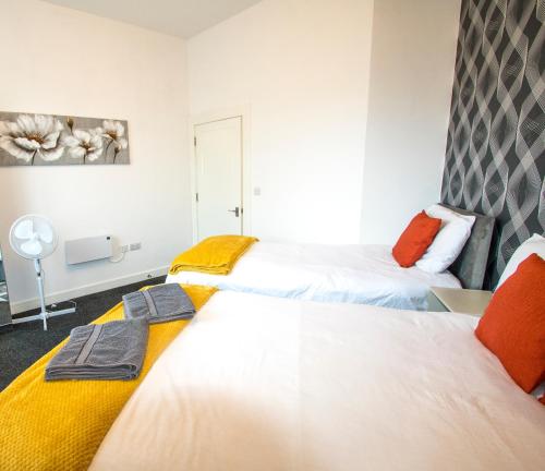 two beds in a room with white and orange at Ideal for groups - Lovely 2 Bedroom Apartment - Free Parking, Transit links, Close to Stadiums in Manchester