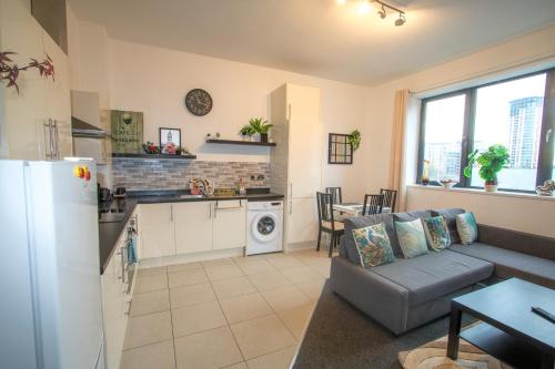 a living room with a couch and a kitchen at Ideal for groups - Lovely 2 Bedroom Apartment - Free Parking, Transit links, Close to Stadiums in Manchester