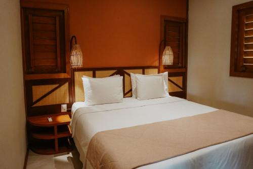a bedroom with a large white bed with two pillows at Jaguaríndia Village in Fortim