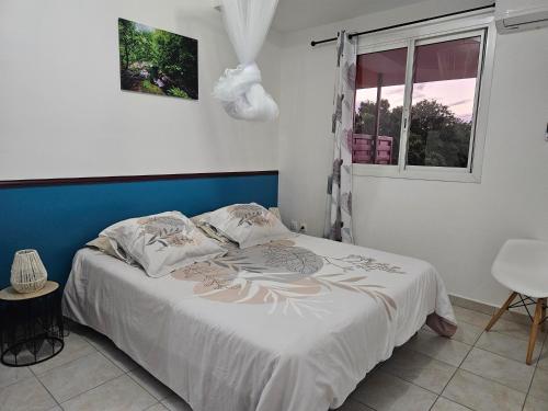 a bedroom with a bed with a blue headboard and a window at Les hauts de beline Salines in Le Gosier