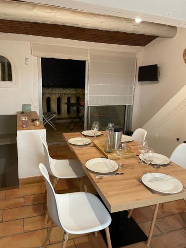 une salle à manger avec une table en bois et des chaises blanches dans l'établissement Nostradamus, à Saint-Rémy-de-Provence