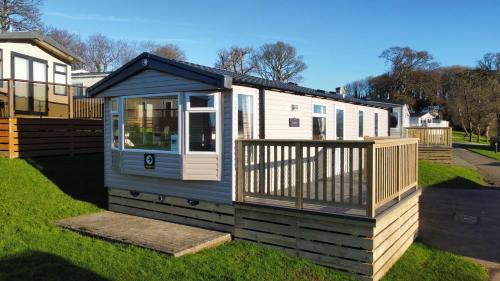 a tiny house with a deck on the grass at Coed Helen Holiday Park in Caernarfon