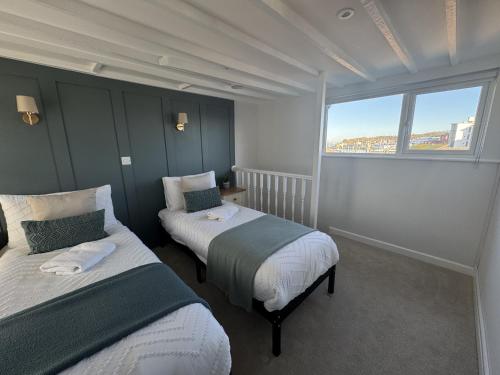 Dos camas en una habitación con una gran ventana. en Driftwood House - Luxury Dog-Friendly Townhouse in Cowes, Steps from Marina, en Cowes