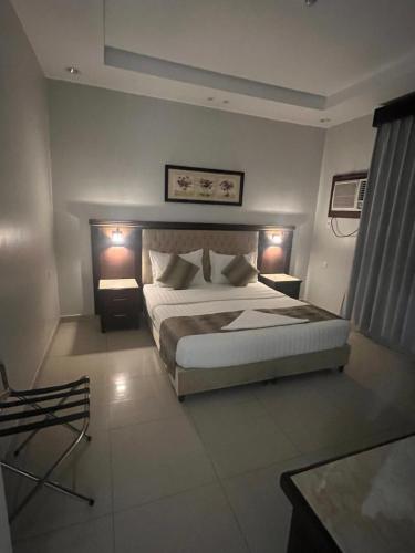 a bedroom with a large bed and two night lights at Dar Karim in Abha