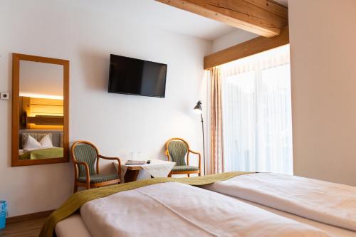 a bedroom with a bed and a mirror and a tv at Hotel Bichlhof in Reit im Winkl
