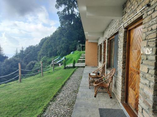 a patio with two chairs and a view of a field at Simba Jungle Lodge, Binsar Wildlife Sanctuary in Binsar