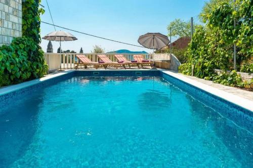 a large swimming pool with chairs and umbrellas in it at Peaceful Villa near Dubrovnik in Trsteno