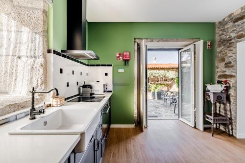 cocina con fregadero blanco y paredes verdes en Casa dos Arcos, en Caminha