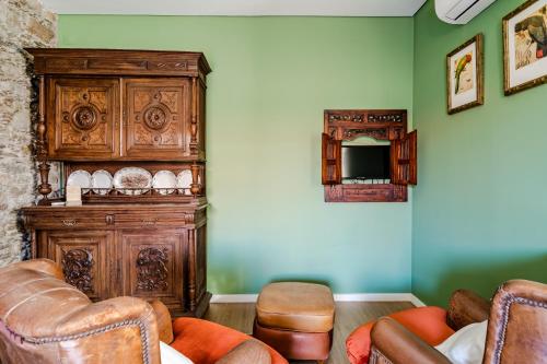 a living room with leather chairs and a wooden cabinet at Casa dos Arcos in Caminha