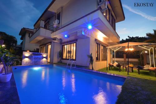 a villa with a swimming pool at night at EKOSTAY - Water Lagoon in Lonavala
