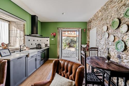 a kitchen with green walls and a table and chairs at Casa dos Arcos in Caminha