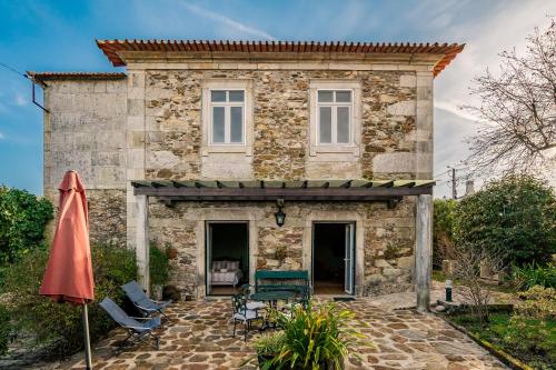 an old stone house with a patio and an umbrella at Casa dos Arcos in Caminha