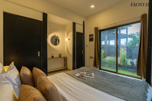 a bedroom with a large bed and a large window at EKOSTAY - Water Lagoon in Lonavala