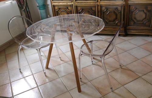 d'une table en verre et de deux chaises sur du carrelage. dans l'établissement Les Roches Fleuries, à Prunières