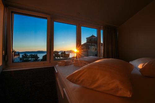 ein Schlafzimmer mit zwei Betten und einem Fenster mit Sonnenuntergang in der Unterkunft Boutique Hostel Forum in Zadar