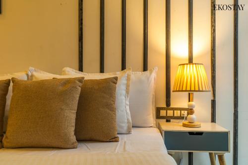 a bed with pillows and a lamp on a table at EKOSTAY - Water Lagoon in Lonavala