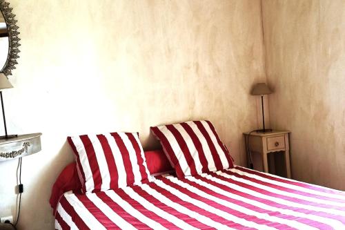 a bed with two red and white striped pillows at joli gîte plain pied in Maférat