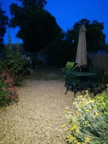 an umbrella and a table and chairs in a garden at joli gîte plain pied in Maférat