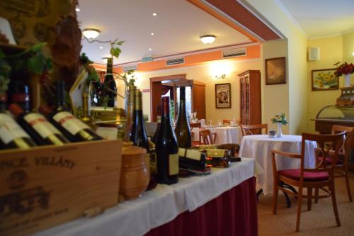 a restaurant with bottles of wine on a table at Hotel Lukács Superior in Kazincbarcika