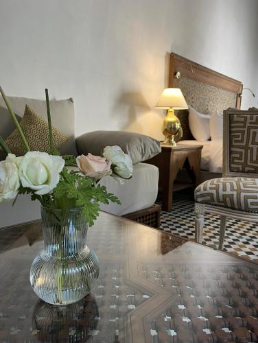 a living room with a vase with flowers on a table at Riad Hanael Garden & Spa in Fès