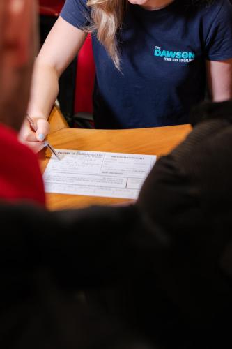 a woman writing on a piece of paper on a table at The Dawson Hostel Galway in Galway