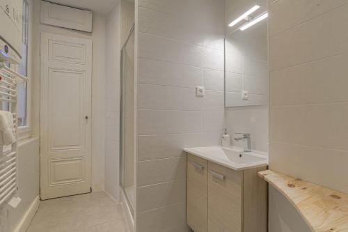 une salle de bain blanche avec un lavabo et un miroir dans l'établissement Cosy et Typique à Cordeliers, à Lyon