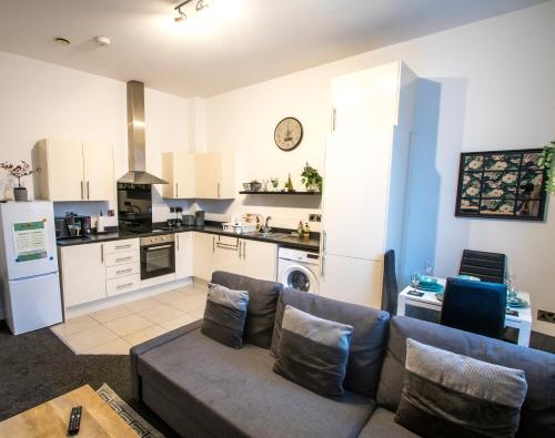 a living room with a couch and a kitchen at Ideal for groups - Modern 2 Bedroom Apartment - Free Parking, Transit links, Close to Stadiums in Manchester
