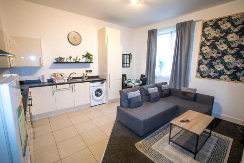 a living room with a couch and a kitchen at Ideal for groups - Modern 2 Bedroom Apartment - Free Parking, Transit links, Close to Stadiums in Manchester