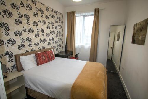 a bedroom with a white bed with a red pillow at Ideal for groups - Modern 2 Bedroom Apartment - Free Parking, Transit links, Close to Stadiums in Manchester