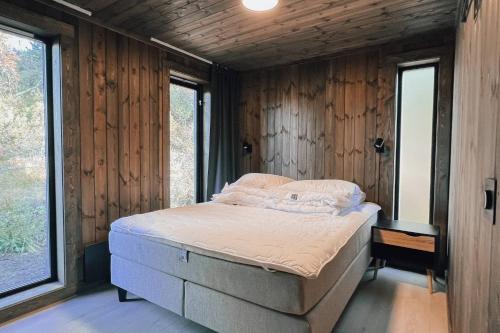 a bed in a room with wooden walls and windows at Modern Mountain Cabin - Outdoor Hot Tub - 8 Beds in Torpo