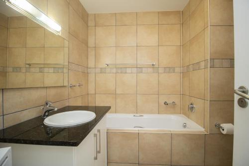 a bathroom with a tub and a toilet and a sink at Hibernian Towers 402 Self Catering Accommodation Strand Western Cape South Africa in Cape Town