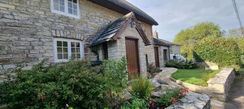 an old stone house with a garden in front of it at The Old Post Office in Wareham
