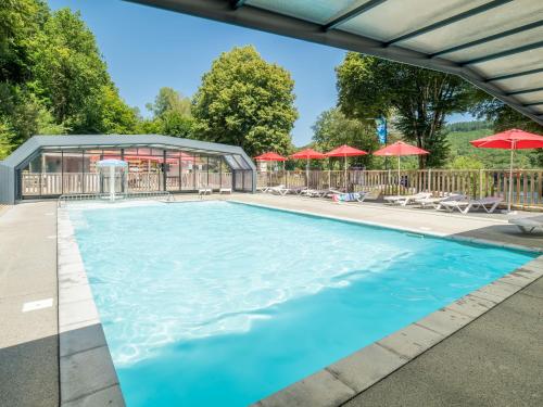 - une piscine avec des parasols rouges dans l'établissement Domaine Résidentiel de Plein Air La Plage, à Treignac