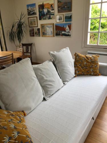 - un canapé avec des oreillers blancs dans le salon dans l'établissement Les Oyats, à Ambleteuse