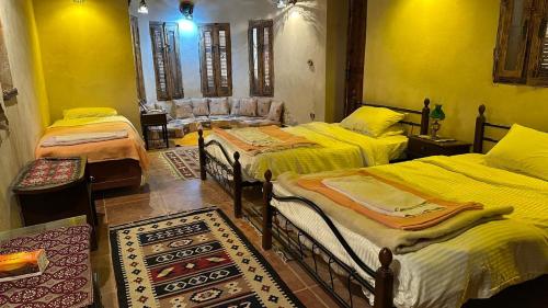 a room with three beds and a couch in it at Paloma Lodge Guest House in Siwa