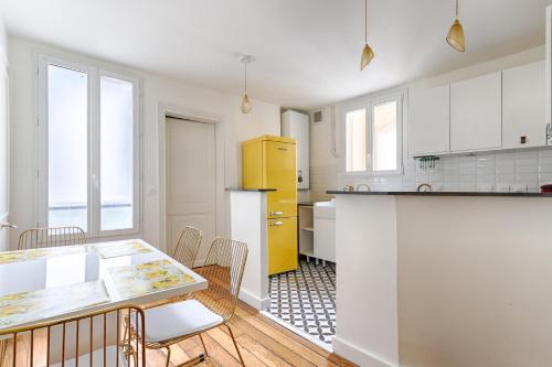 La cuisine est équipée de placards blancs et d'un réfrigérateur jaune. dans l'établissement Sentier Gare Est Magnifique Appartement 2BR, à Paris
