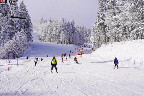 a group of people skiing down a snow covered slope at Hotel Han Bjelašnica in Bjelašnica
